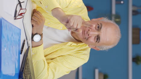 Vertical-video-of-Home-office-worker-old-man-coming-up-with-idea-looking-at-camera.